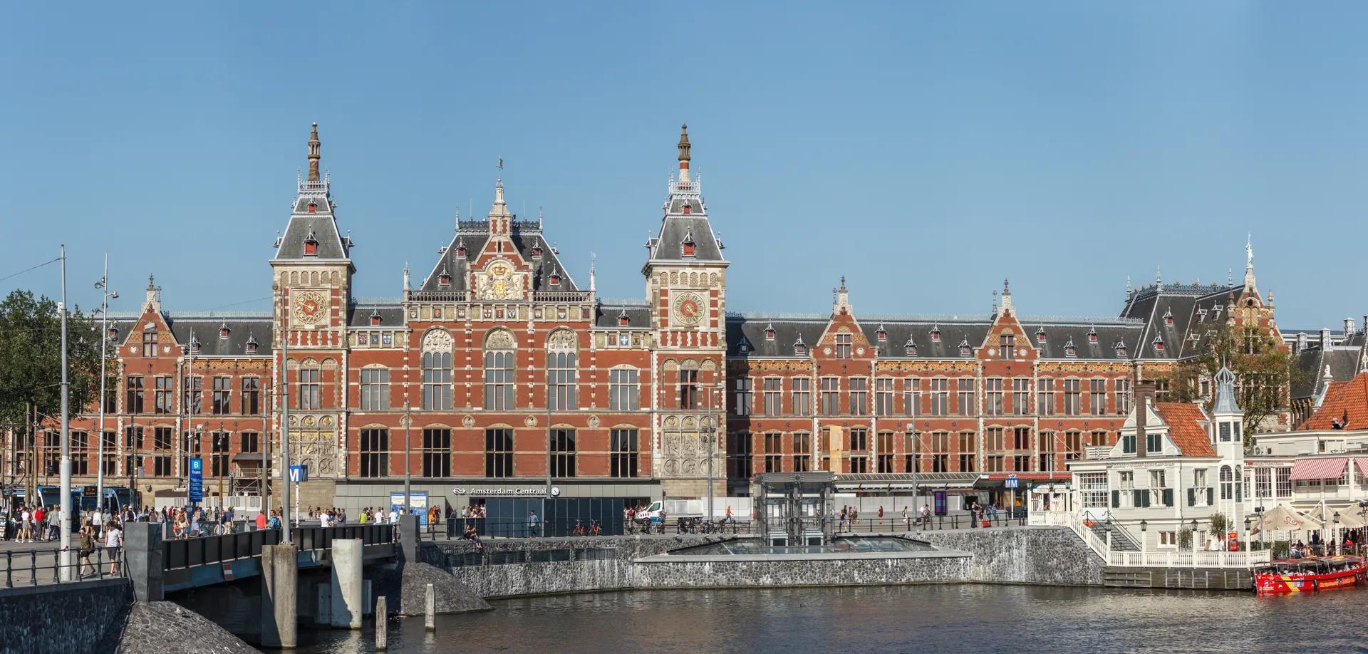 The red-brick facade of Amsterdam Centraal station seen across the water