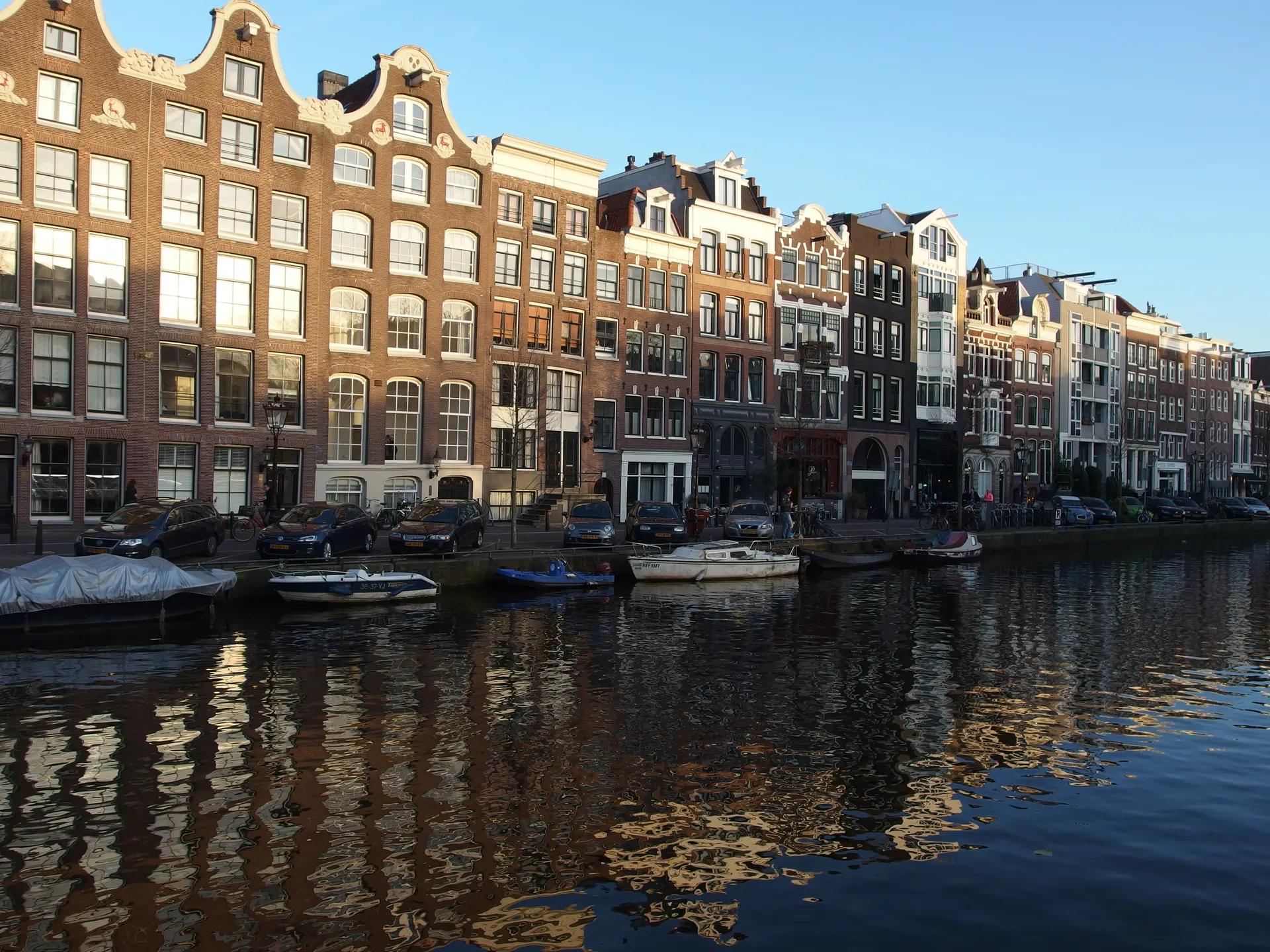 Gabled canal houses reflected in a Jordaan canal under a blue sky