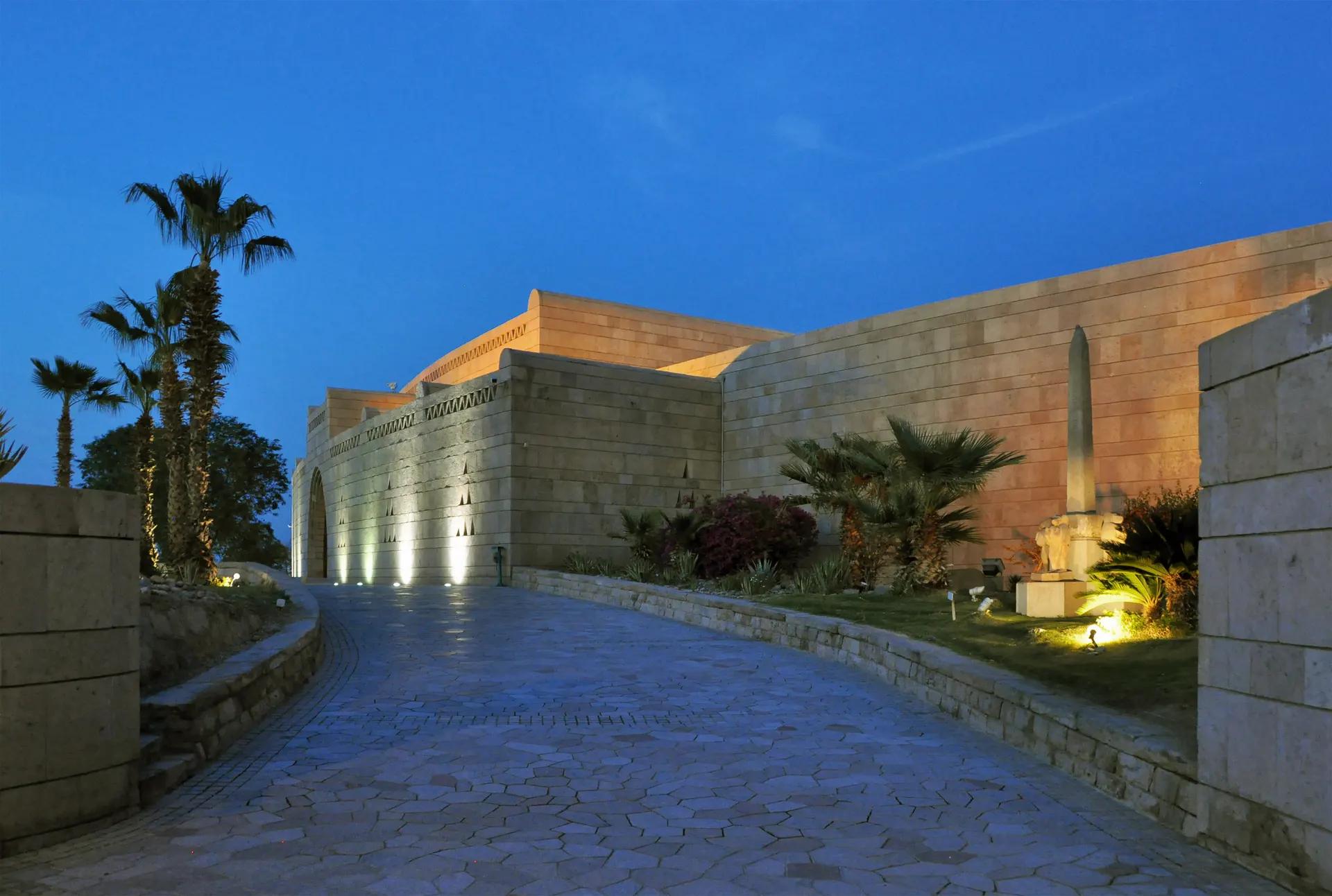 Entrance of the Nubian Museum in Aswan at dusk with palms and an obelisk