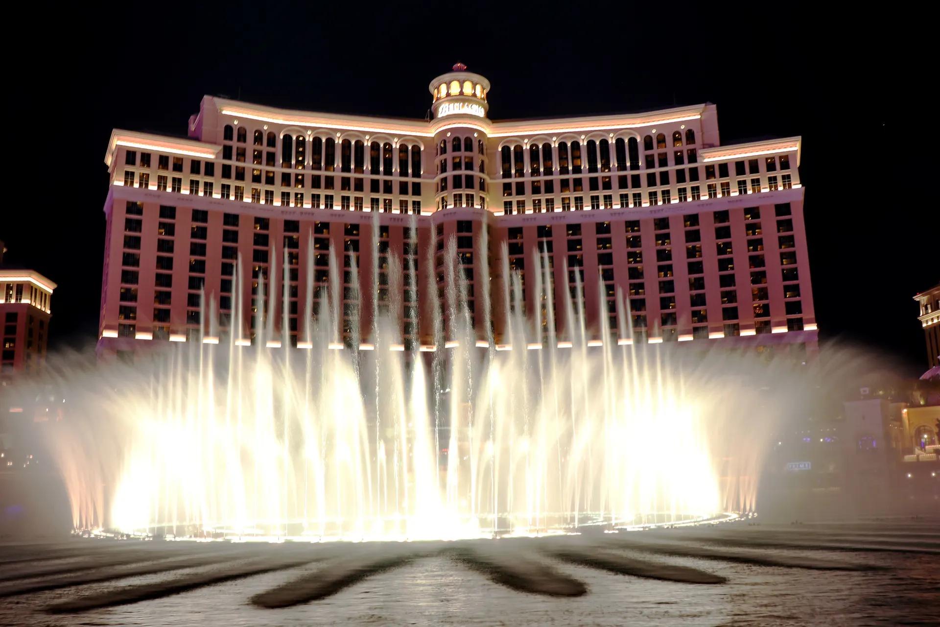 Fountains of Bellagio lit up in front of the Bellagio hotel at night