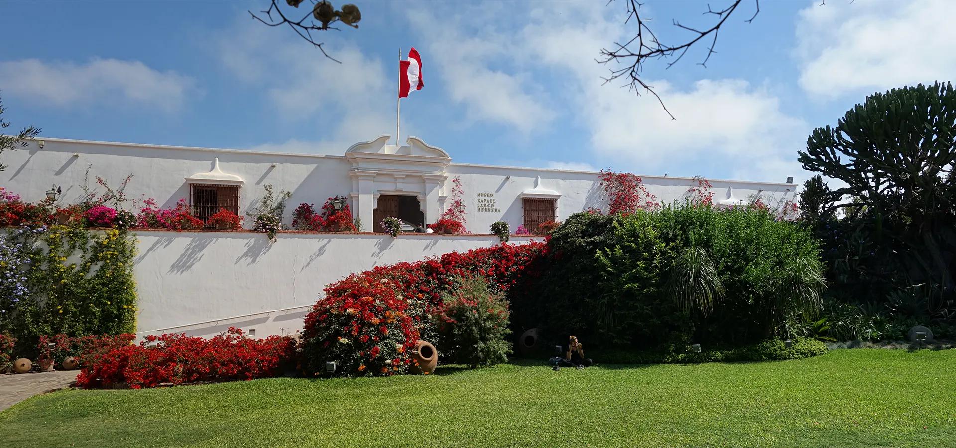 White colonial building of the Larco Museum with red bougainvillea
