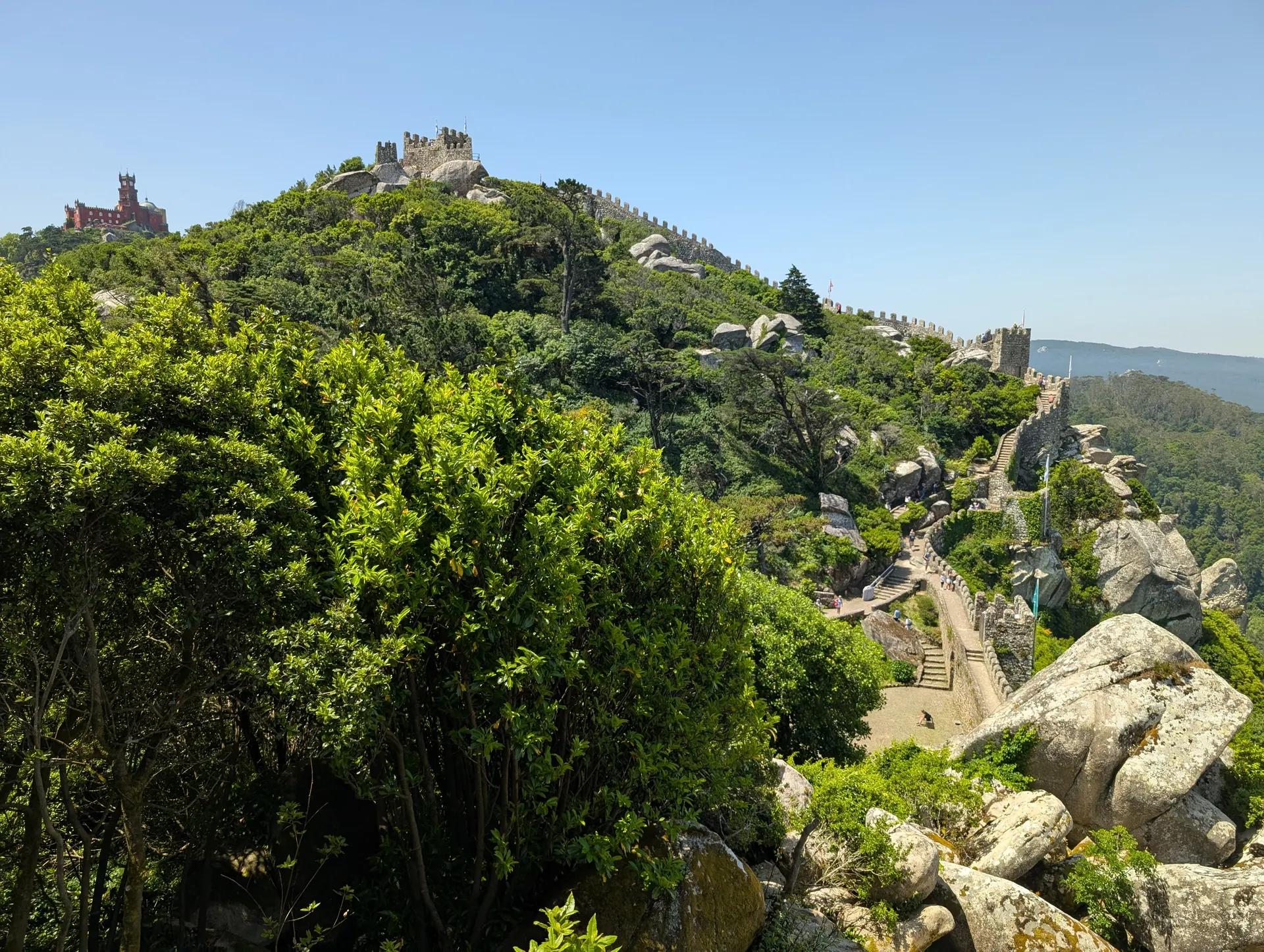 Walls of the Castle of the Moors winding along a wooded ridge, Pena Palace in the distance