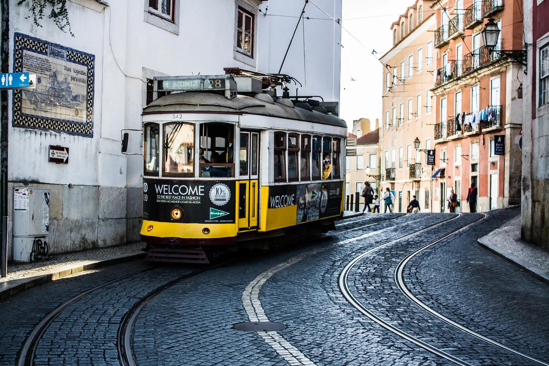 Yellow tram 28 rounding a cobbled curve in Alfama