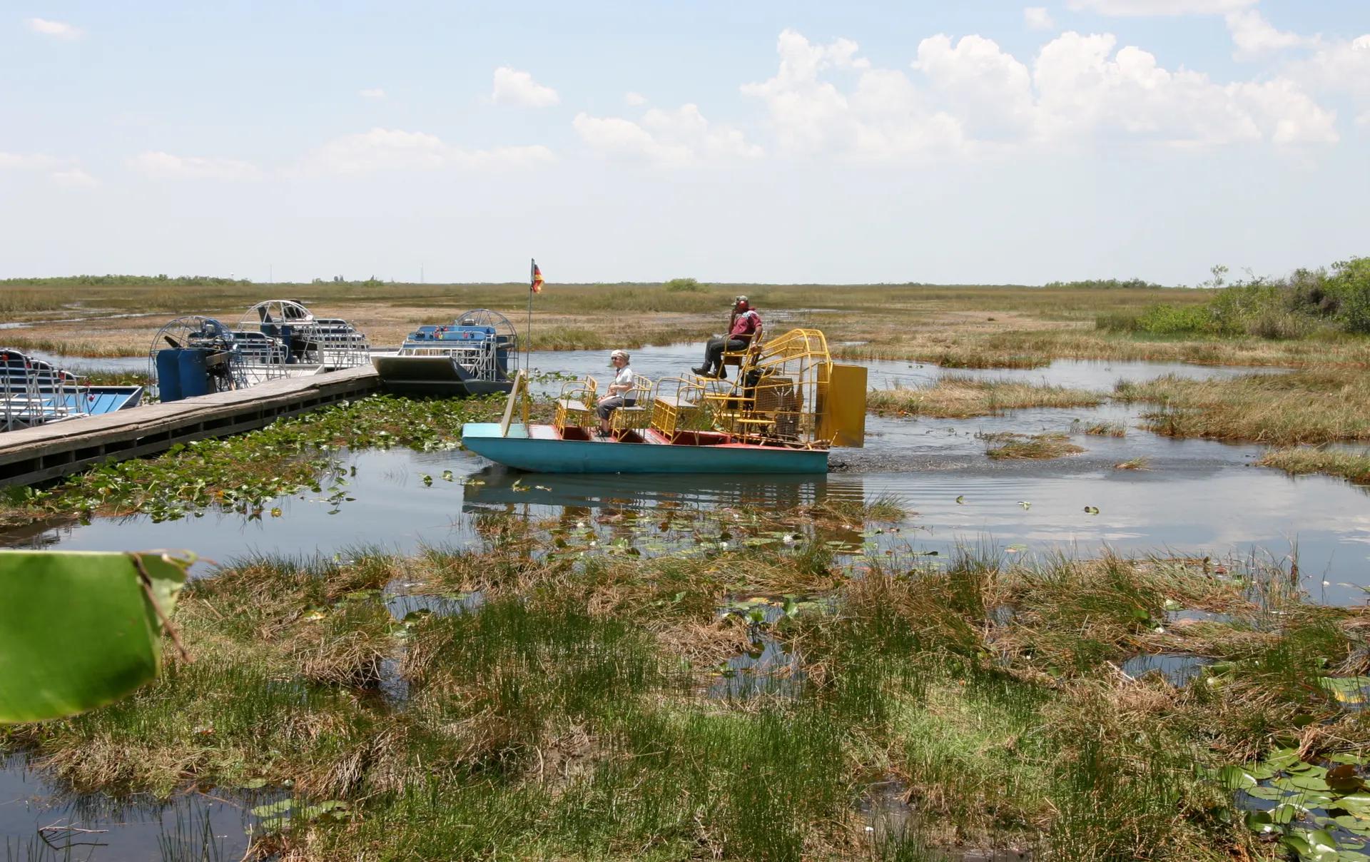 Airboat moving through Everglades sawgrass near a dock