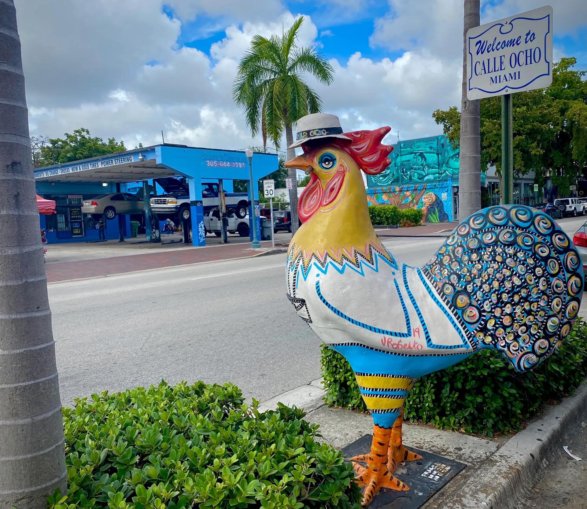 Painted rooster statue beside the Welcome to Calle Ocho sign in Little Havana