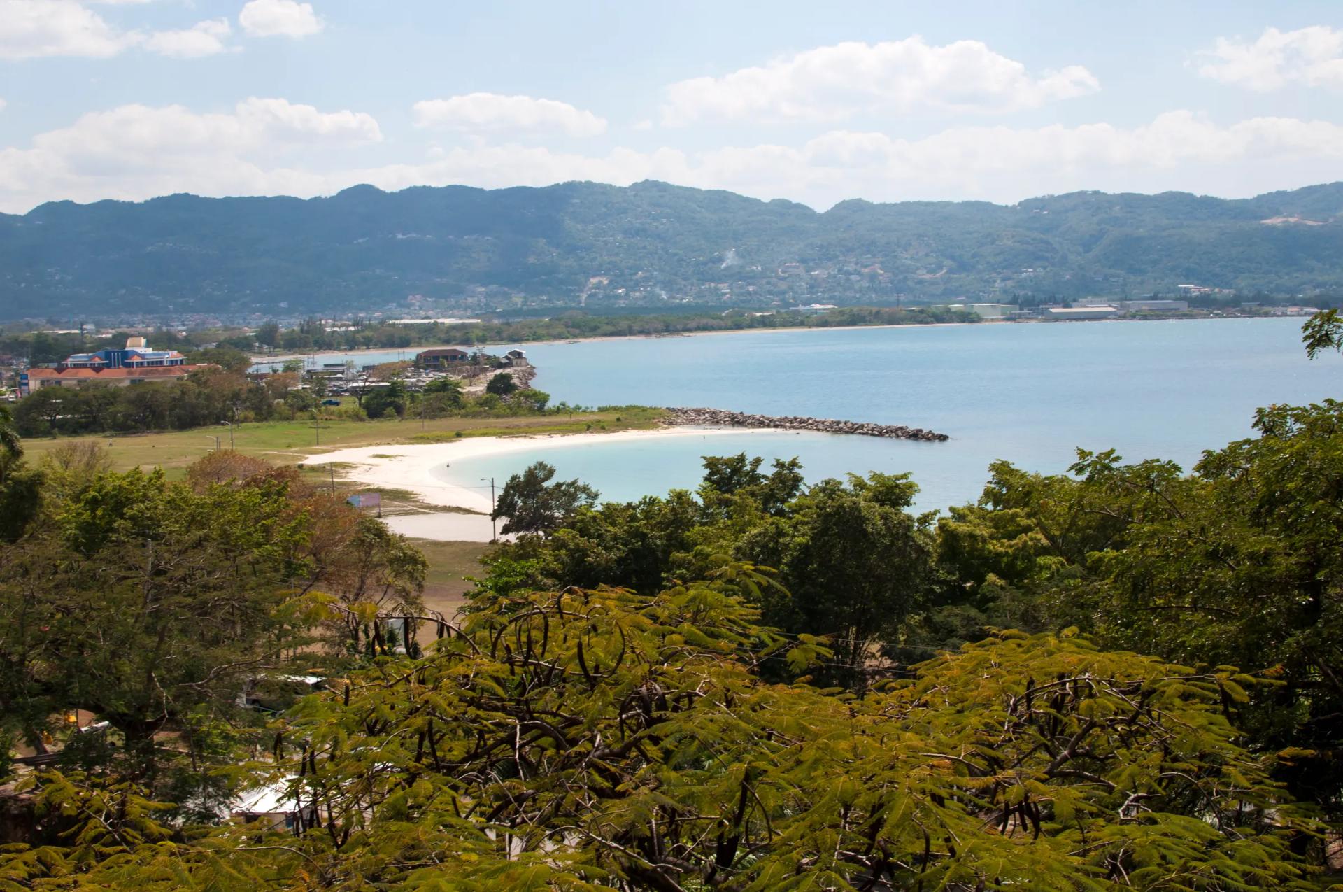 View over Montego Bay with a white beach, blue water and green hills behind