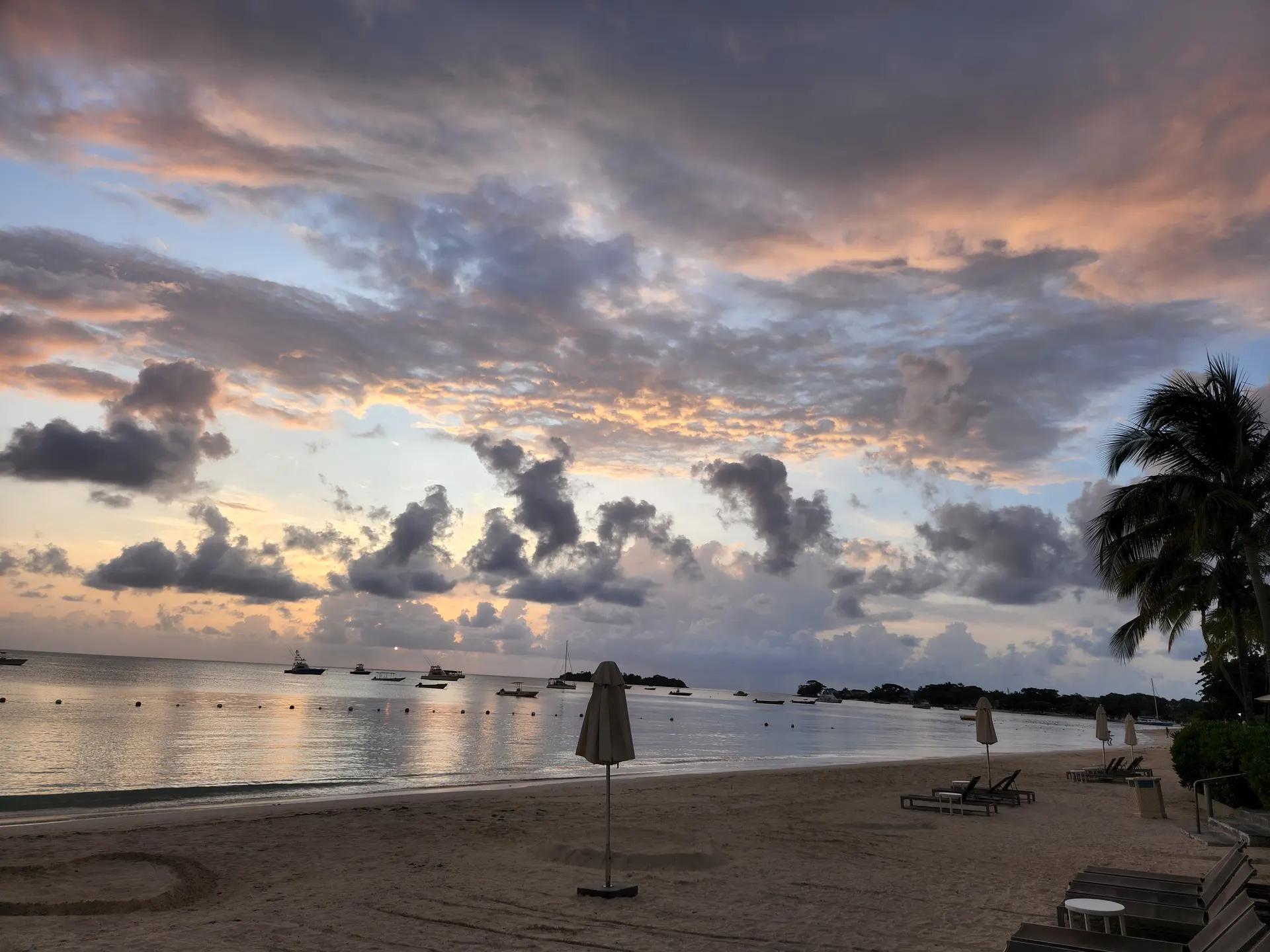 Seven Mile Beach in Negril at dusk with sun loungers and boats on calm water