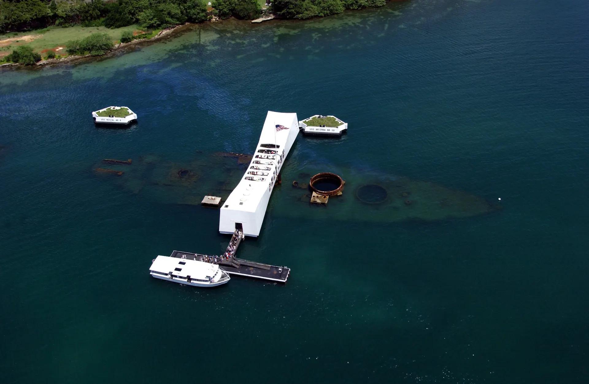 Aerial view of the white USS Arizona Memorial over the sunken battleship
