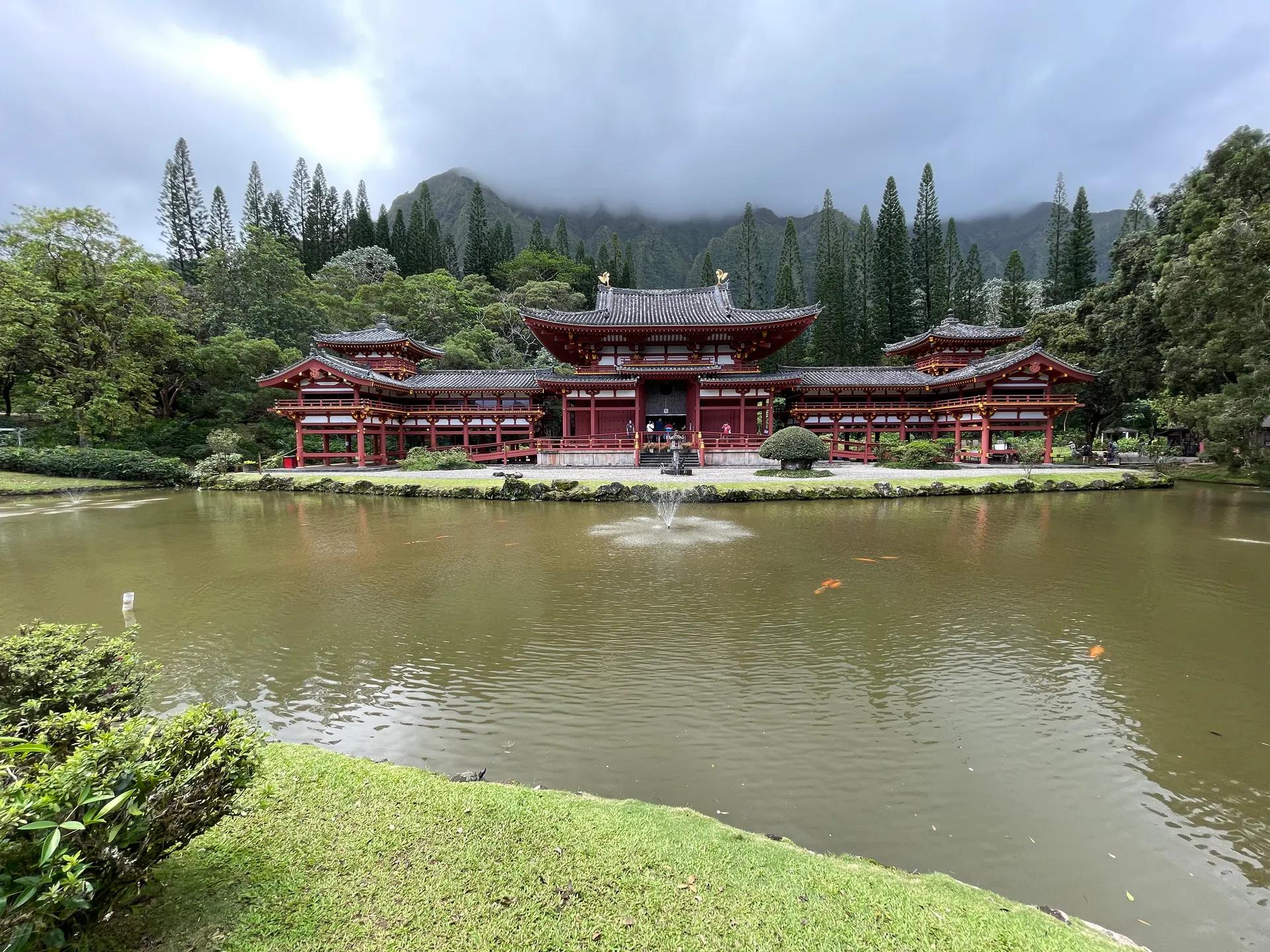 Red Byodo-In Temple behind a pond with forested cliffs