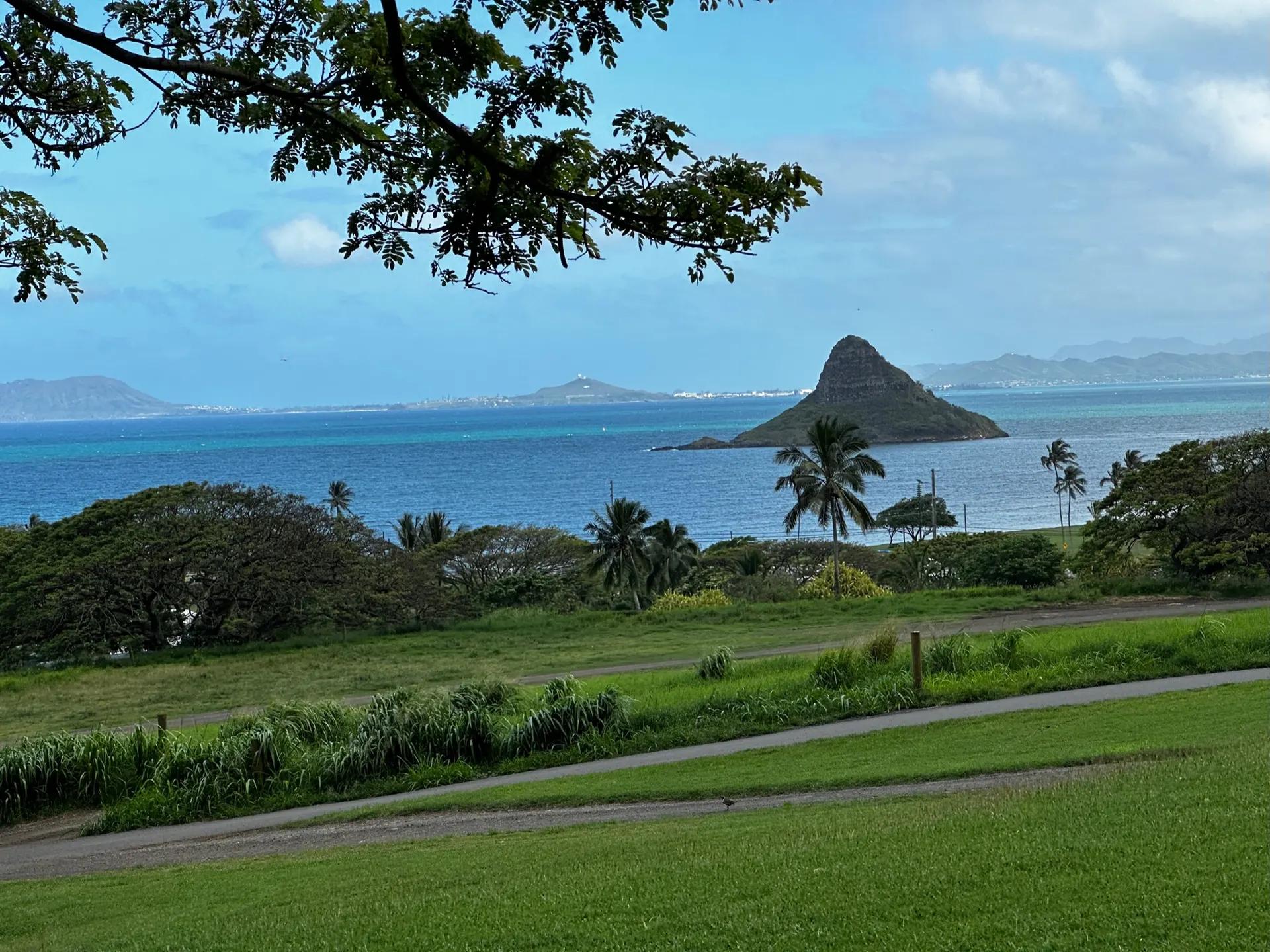 Green lawns at Kualoa Ranch with a small cone-shaped island in the bay