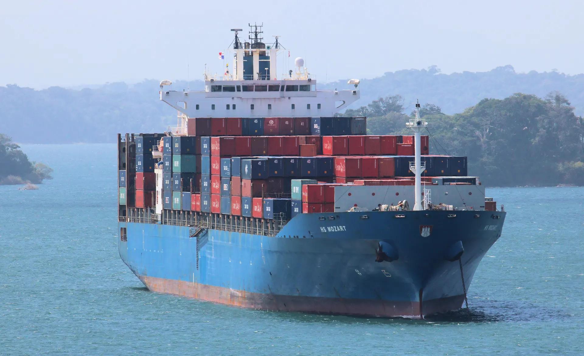 Container ship crossing Gatun Lake between forested islands