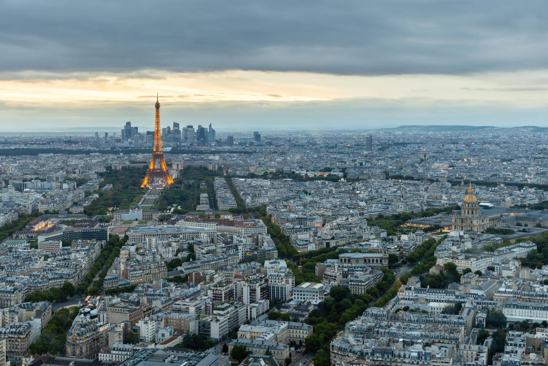 Paris at dusk from the top of the Tour Montparnasse, with the lit Eiffel Tower, the Invalides dome and La Défense behind