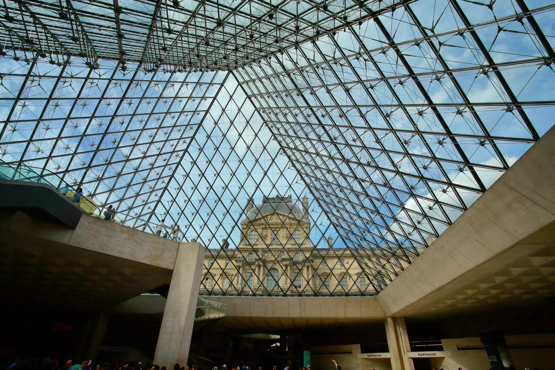Louvre Palace seen through the glass of the Louvre Pyramid from the entrance hall below