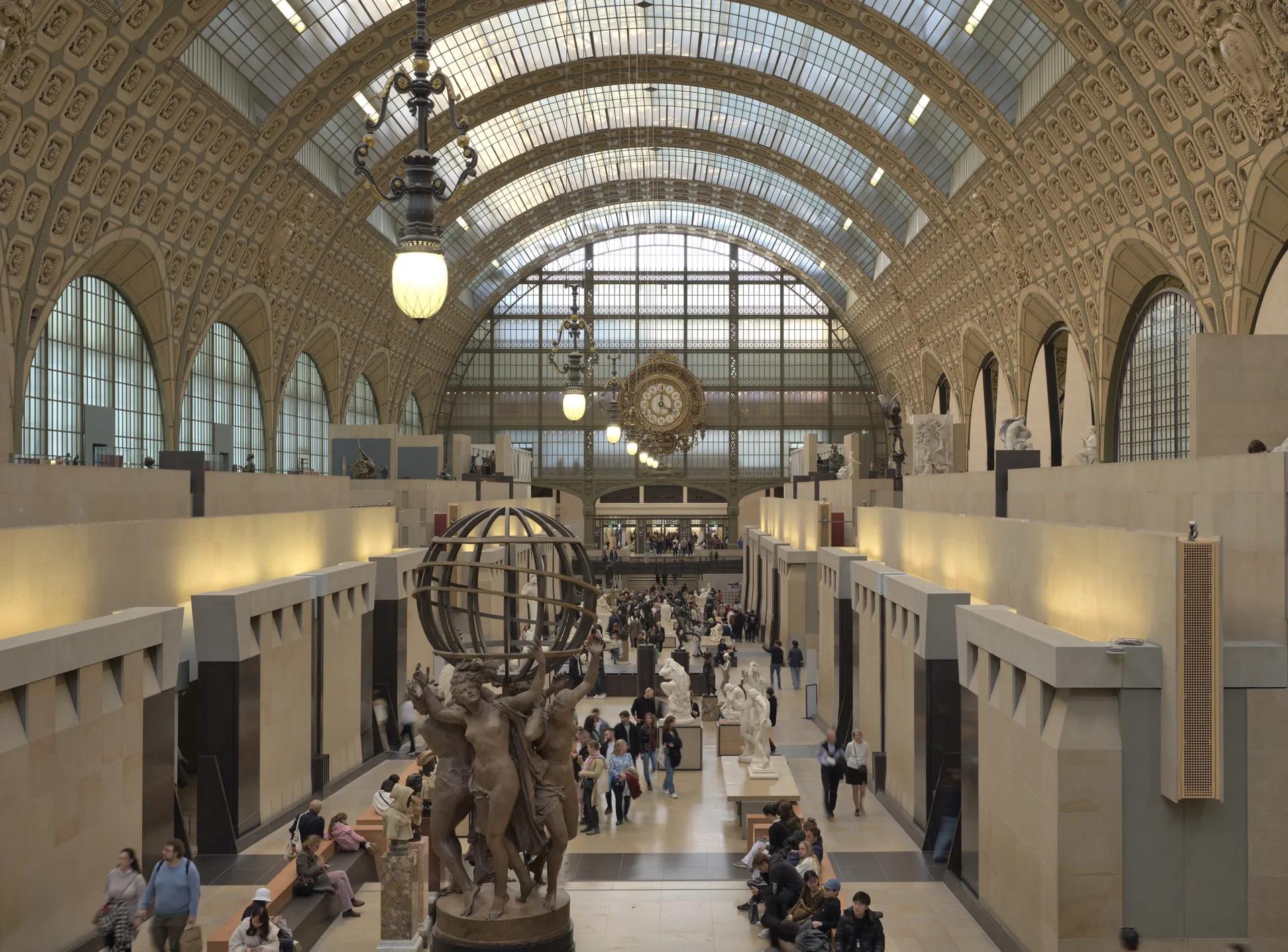 Main hall of the Musée d'Orsay with sculptures under the glass barrel vault and the large station clock