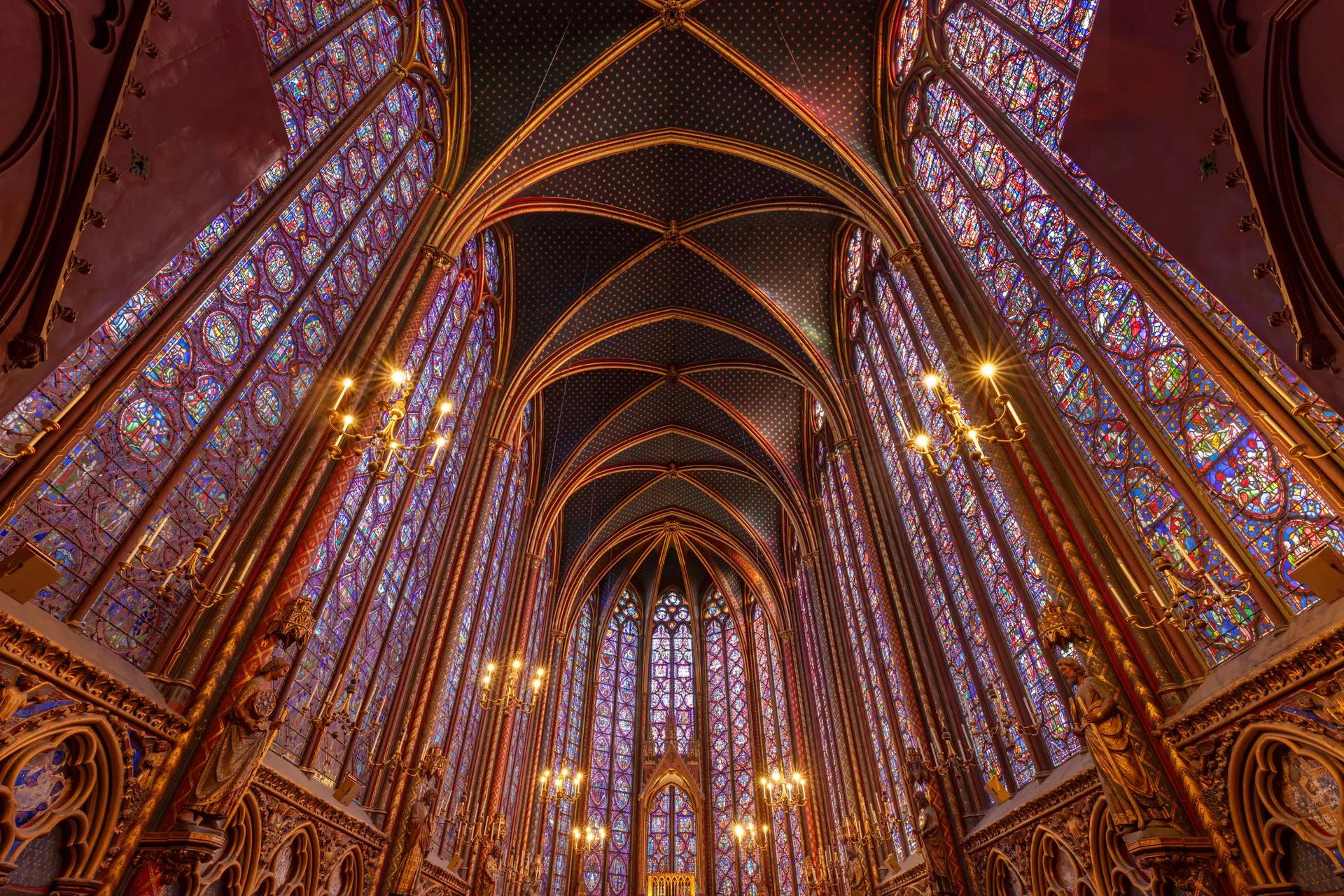 Upper chapel of the Sainte-Chapelle with tall stained-glass windows and a blue starred vault