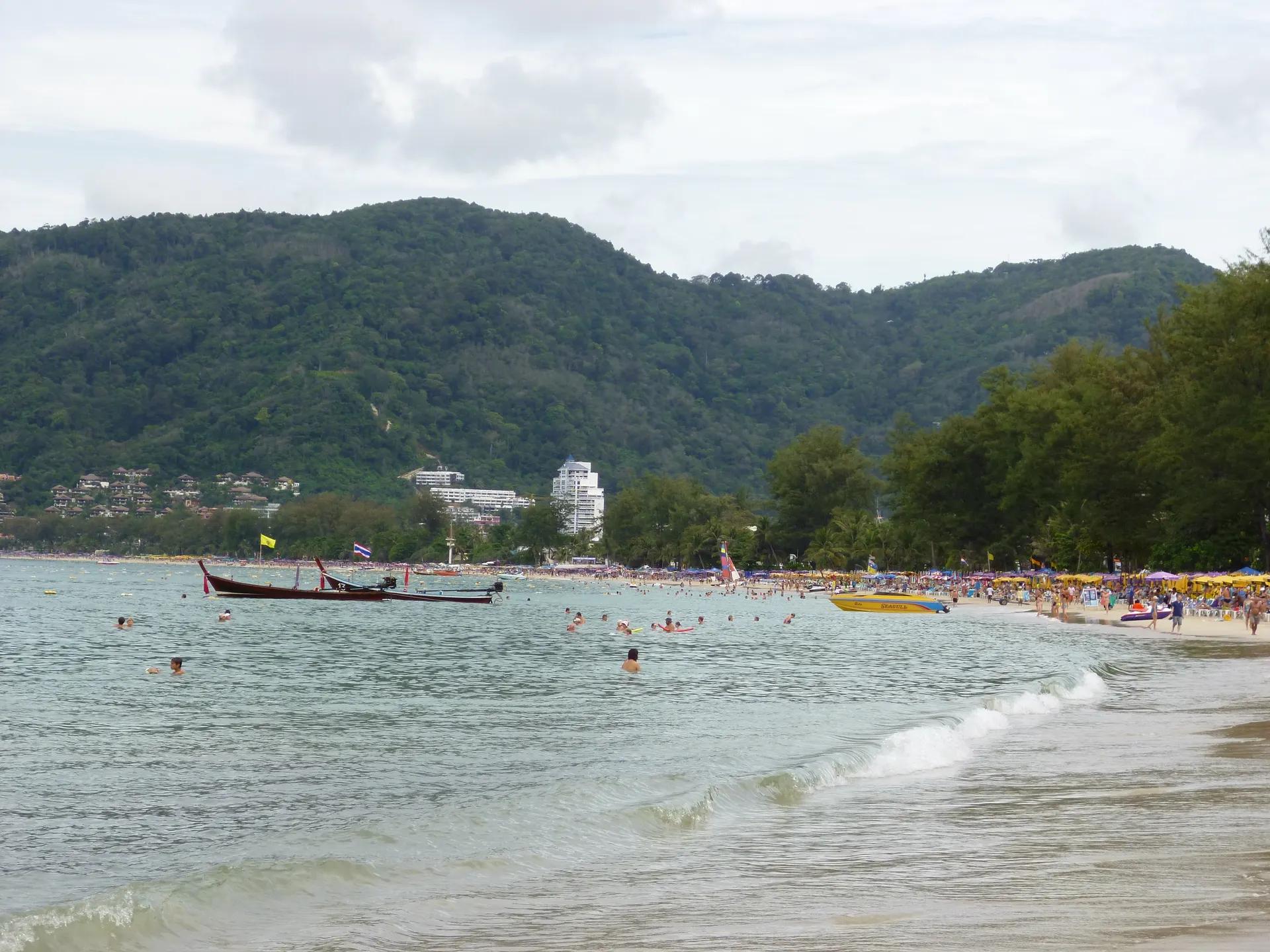 Patong Beach with long-tail boats and green hills behind