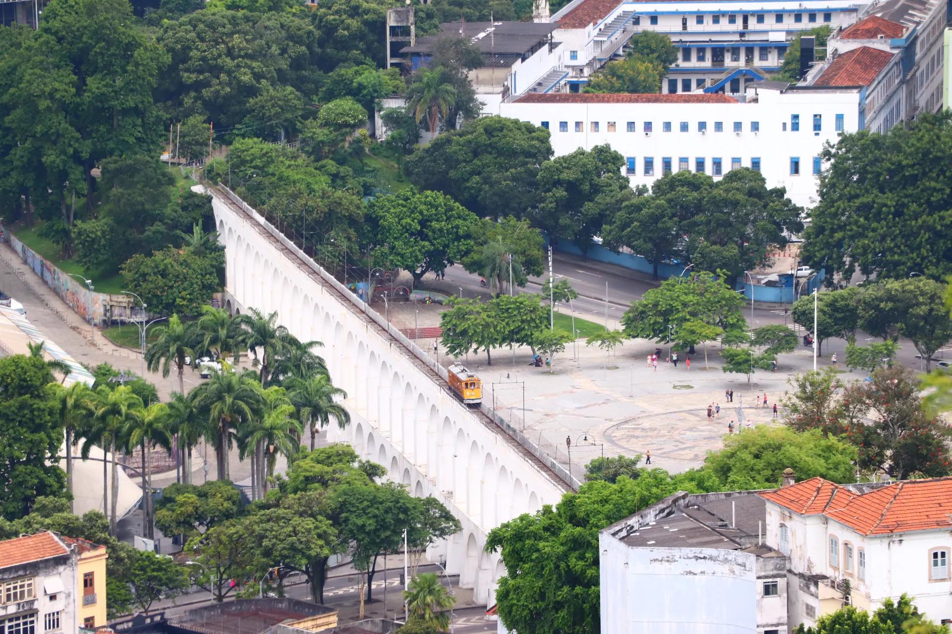 Yellow Santa Teresa tram crossing the white Arcos da Lapa aqueduct