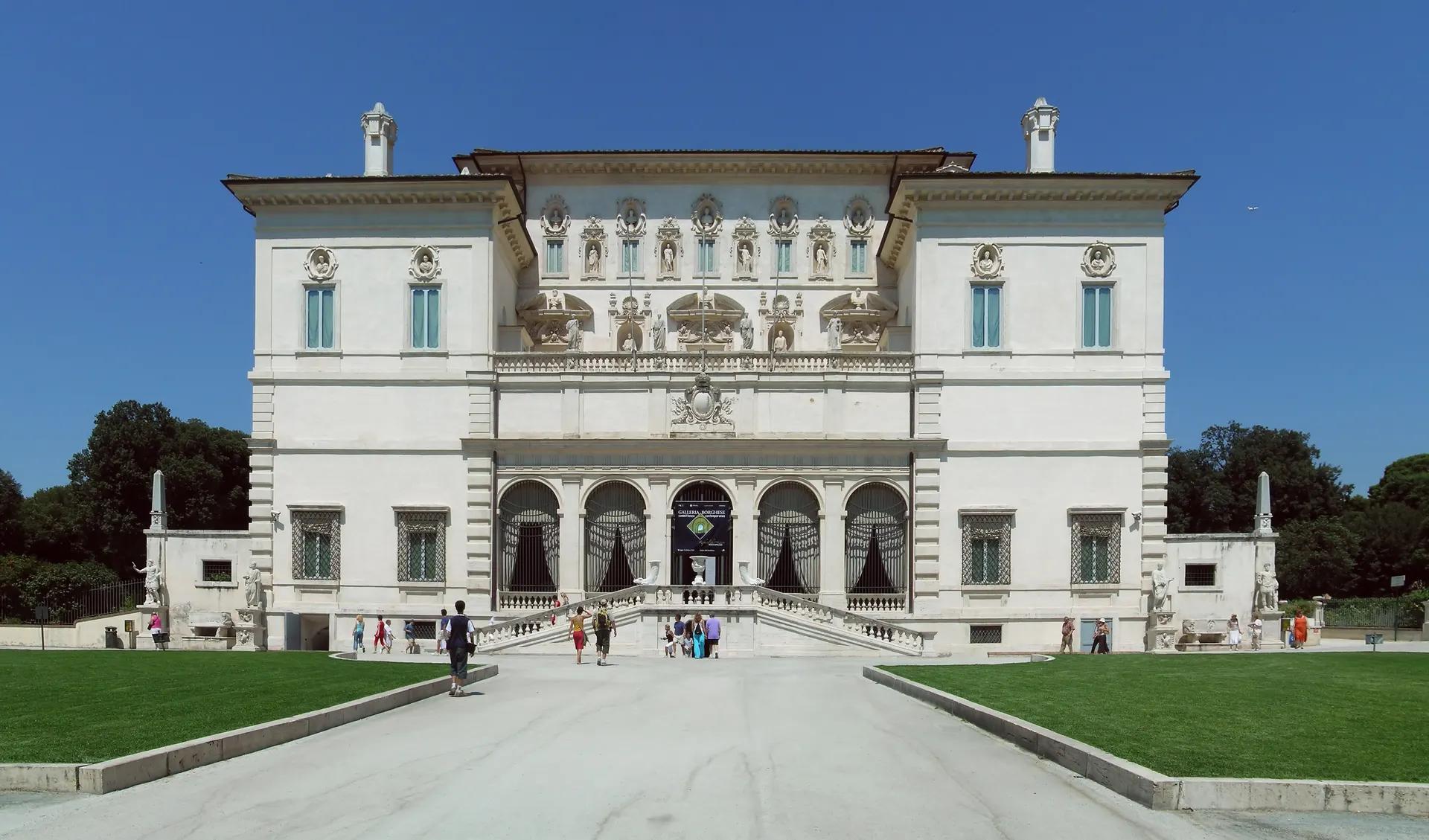 The white facade of the Galleria Borghese villa with lawns in front