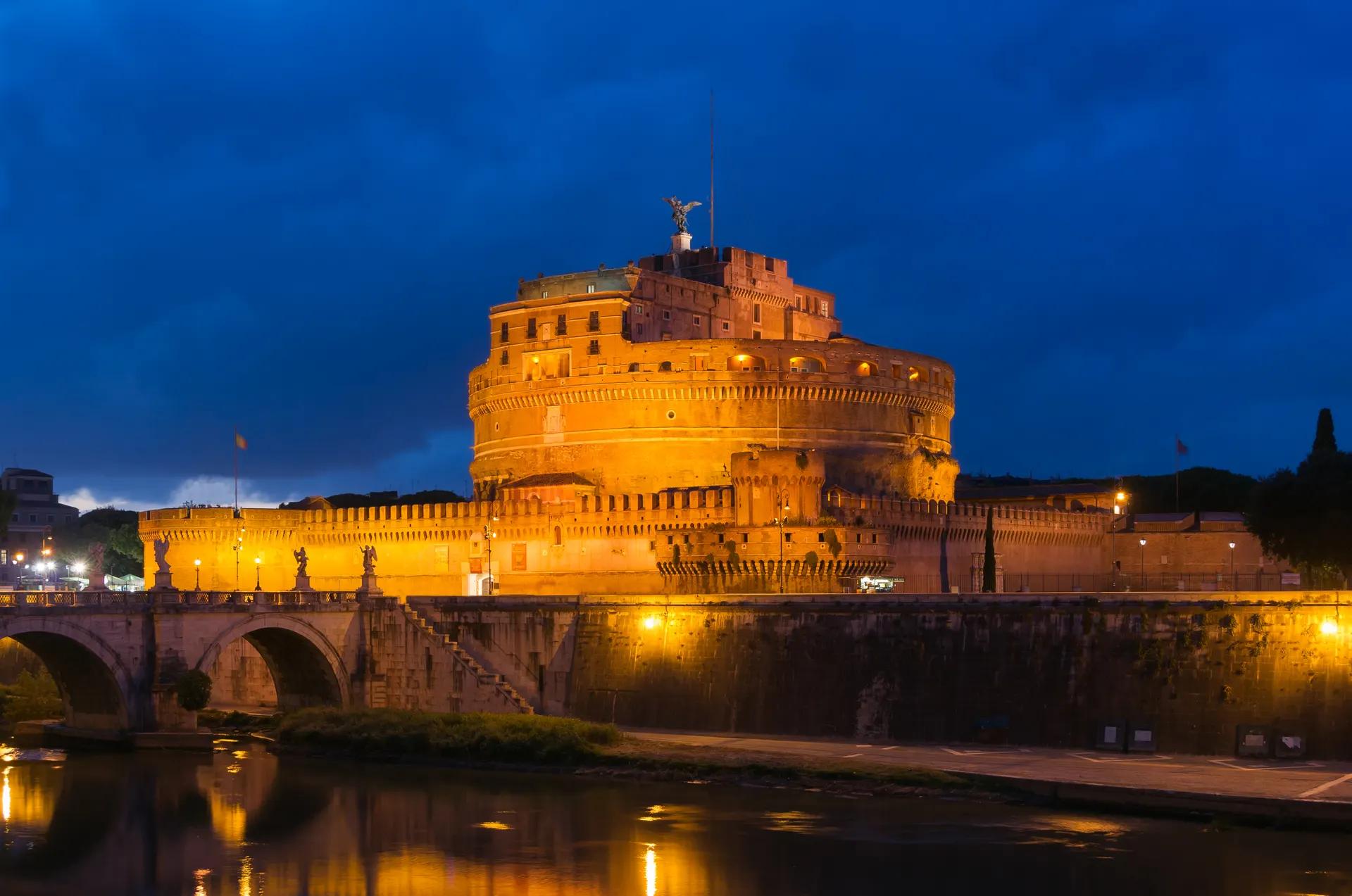 Castel Sant'Angelo lit up at dusk above the Tiber