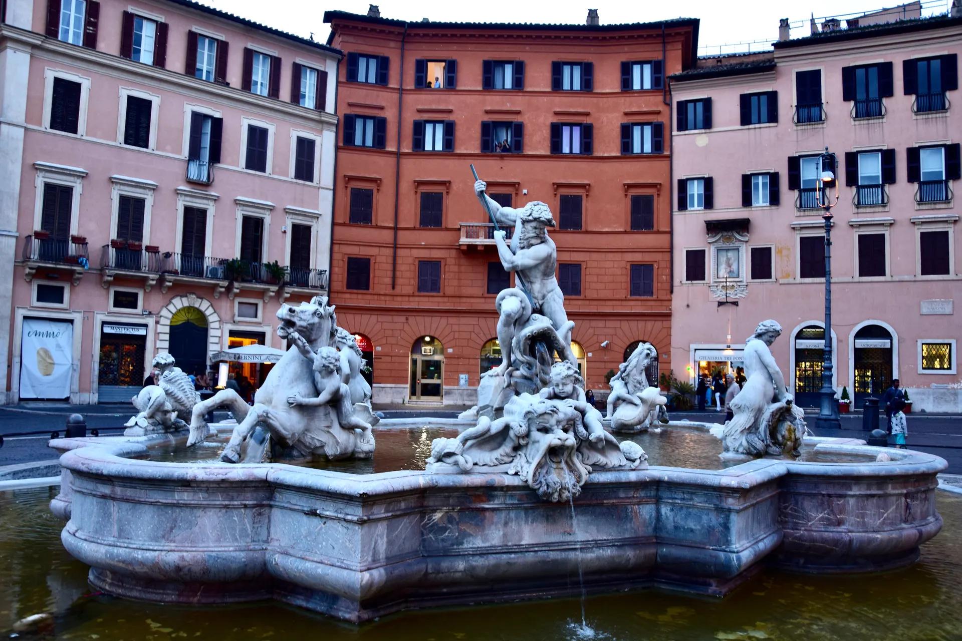 The Fountain of Neptune in Piazza Navona with coloured buildings behind