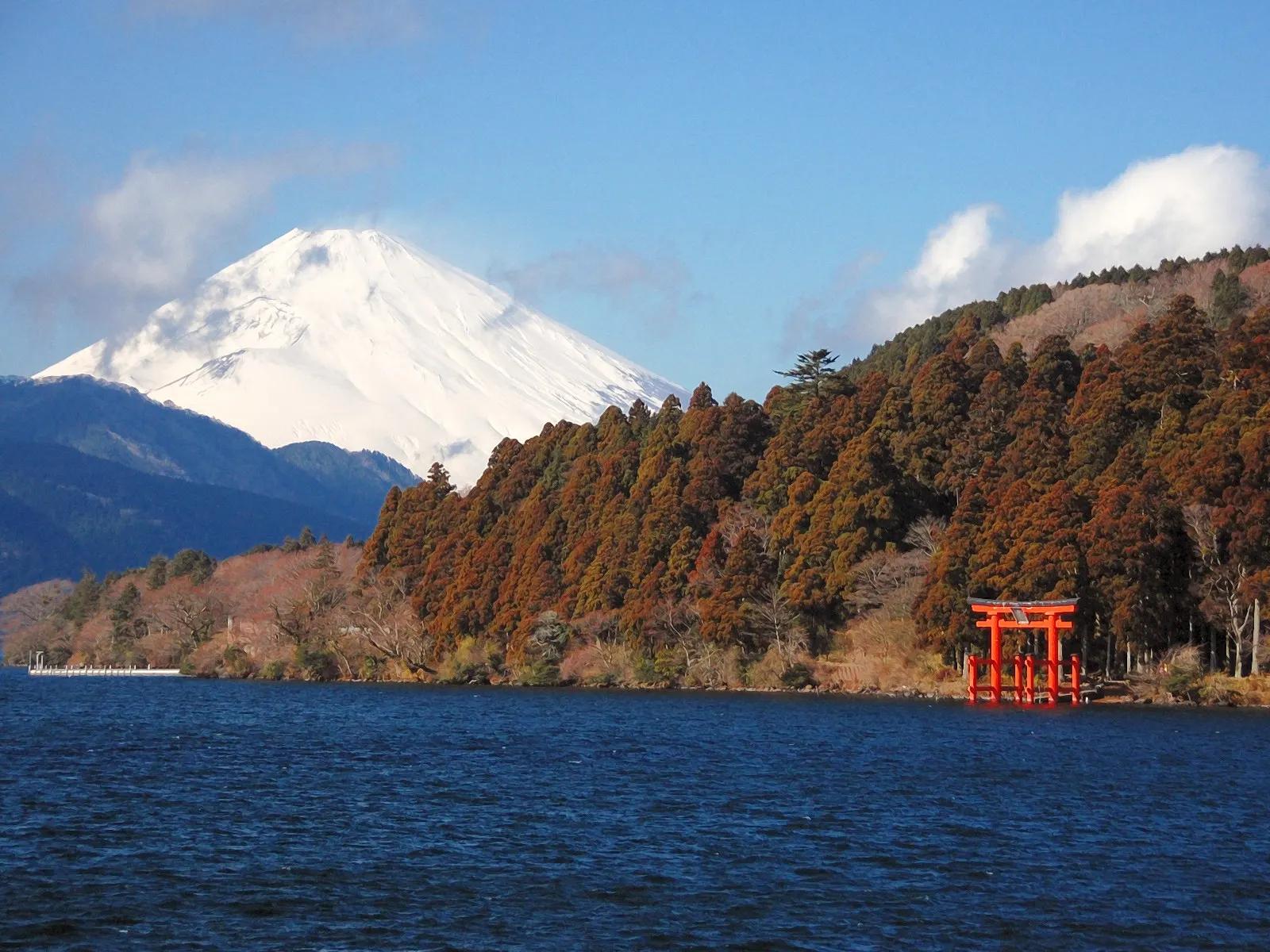 Red torii at the edge of Lake Ashi with snowy Mount Fuji behind