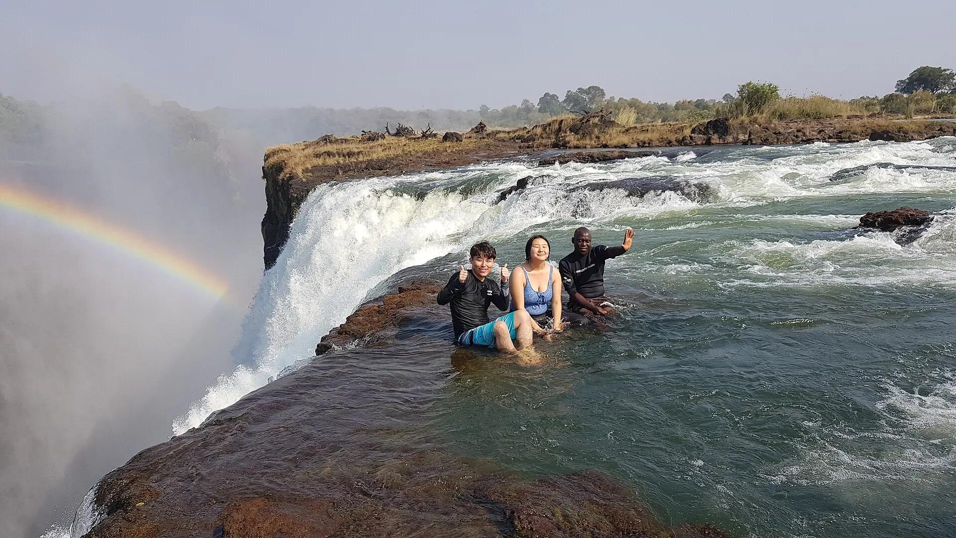Visitors sitting in Devil’s Pool on the edge of Victoria Falls